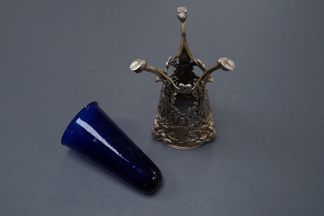 A late Victorian continental pierced silver posy vase, with blue glass liner, decorated with cupids, ram's heads and birds, on tripod supports with hoof feet, import marks for William Moering, London, 1898, height 15.2cm